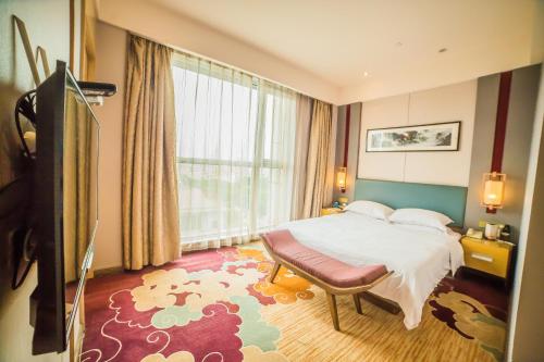 um quarto de hotel com uma cama e uma grande janela em 济宁银座佳悦精选酒店 em Jining