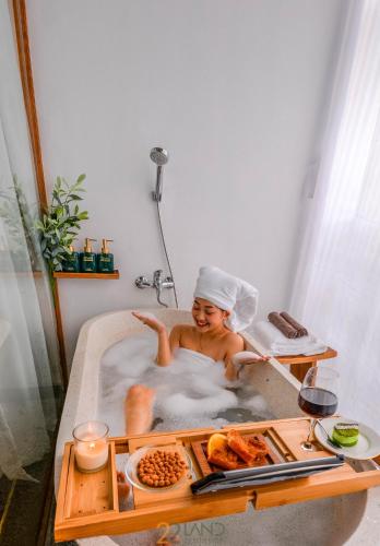a woman sitting in a bathtub with a tray of food at 22Land Hotel & Residence in Hanoi