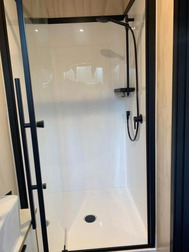 una doccia bianca con porta in vetro in bagno di Snowman Cabins a Ohakune