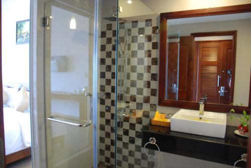 a bathroom with a shower and a sink and a mirror at Canary Beach Resort in Mui Ne