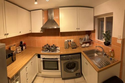 een keuken met een wastafel en een wasmachine bij Heritage holiday house in Pembrokeshire