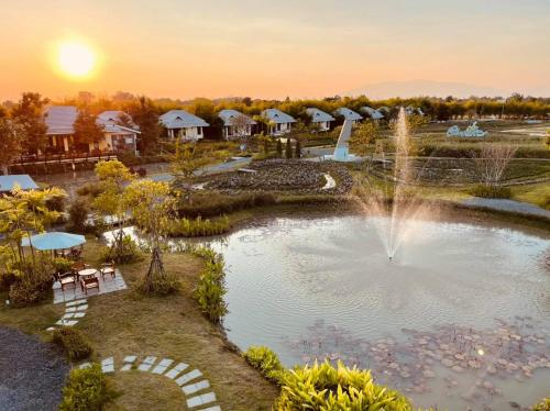 un estanque con una fuente frente a un complejo en Chapulin Natural Resort en Chiang Mai