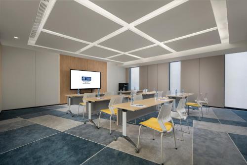 a conference room with tables and chairs and a screen at Holiday Inn Express Nanchang Riverside by IHG in Nanchang