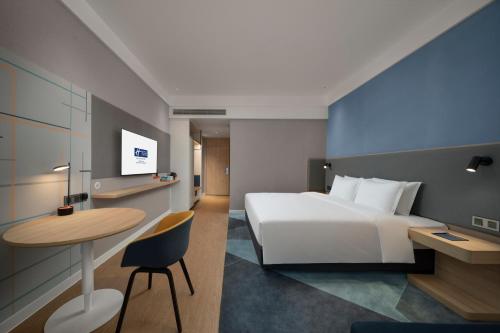 a hotel room with a white bed and a table at Holiday Inn Express Nanchang Riverside by IHG in Nanchang