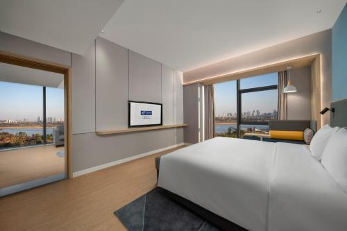 a bedroom with a white bed and large windows at Holiday Inn Express Nanchang Riverside by IHG in Nanchang