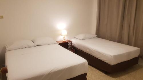 two beds in a hotel room with a lamp on a table at Villa del Mar Departamento 1 I in Salinas