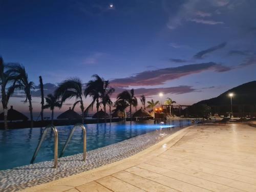 a resort swimming pool at night with palm trees at Apartamento en Samaria Club de Playa Privada Salida Directa al Mar en Pozos Colorados cerca a Zazue, Estelar, Playa Bello Horizonte, Cabo Tortuga #1 in Santa Marta