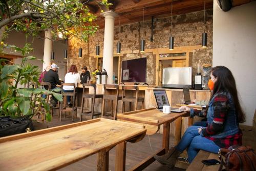 a woman sitting at a table with a laptop at The Coffee Bean Hostel in San Cristóbal de Las Casas