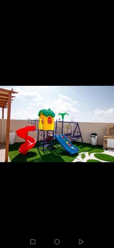 a playground with two slides and a play equipment at Estrahet Al Haitham in Al Qal‘ah