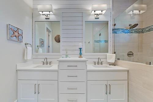 a white bathroom with two sinks and a mirror at Palmilla Beach Resort in Port Aransas
