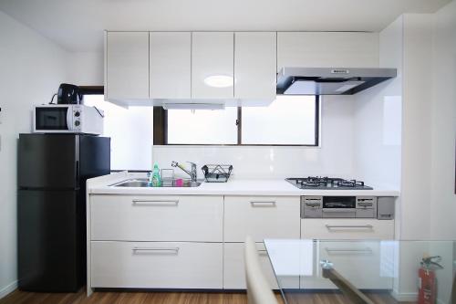 a kitchen with white cabinets and a black refrigerator at MUMU HOUSE in Tokyo