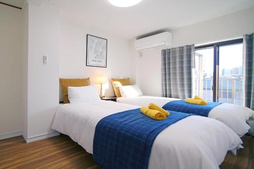 Dos camas en una habitación de hotel con almohadas amarillas. en MUMU HOUSE en Tokio