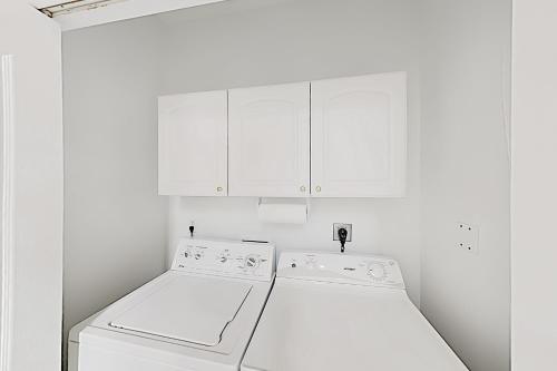 a kitchen with white cabinets and a washer and dryer at Acapulco Unit A in South Padre Island