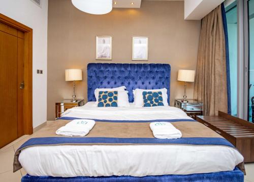 a large bed with a blue headboard in a room at Stylish and Sleek 1 Bed + Study near the JBR beach in Dubai