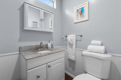 a white bathroom with a toilet and a sink at OB Bungalow in San Diego