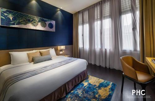 una habitación de hotel con una cama grande y una silla en Ropewalk Piazza Hotel by PHC en George Town