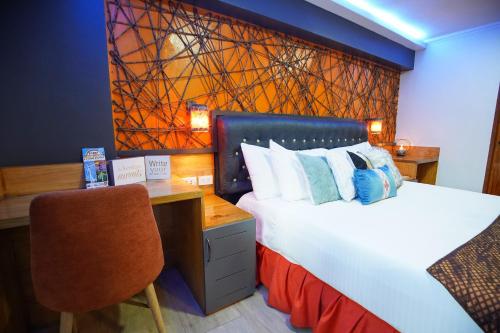 a bedroom with a bed with a desk and a chair at CLOCKWORKORANGE Luxury Suites 4-Minutes Away To Airport in Mactan