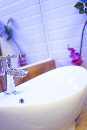 a white bathroom sink with a faucet and a mirror at CLOCKWORKORANGE Luxury Suites 4-Minutes Away To Airport in Mactan