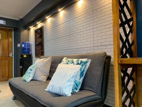 a couch with pillows on it next to a brick wall at CLOCKWORKORANGE Luxury Suites 4-Minutes Away To Airport in Mactan