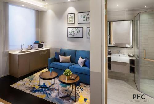 a living room with a blue couch and a bathroom at Ropewalk Piazza Hotel by PHC in George Town