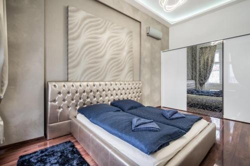 a bedroom with a large bed with blue sheets at Opera Luxury Apartment in Budapest