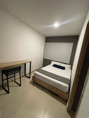 a small bedroom with a bed and a desk at HOTEL MEDELLIN CENTRAL in Medellín