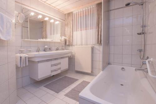 La salle de bains est pourvue d'un lavabo, d'une douche et d'une baignoire. dans l'établissement Appartement Wimreiter, à Saalbach-Hinterglemm