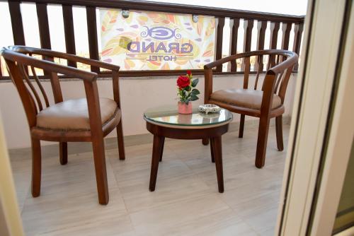 two chairs and a table with a vase of flowers on a balcony at Grand Hotel Ras Elbar in Ras El Bar