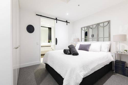 a white bedroom with a large bed with black shoes on it at The Port Melbourne Experience in Melbourne