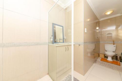 a white bathroom with a toilet and a sink at Stay at 11 on Gull in Cape Town