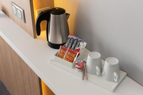 a shelf with a coffee pot and cups on it at Holiday Inn Express - Rouen Centre - Rive Gauche by IHG in Rouen