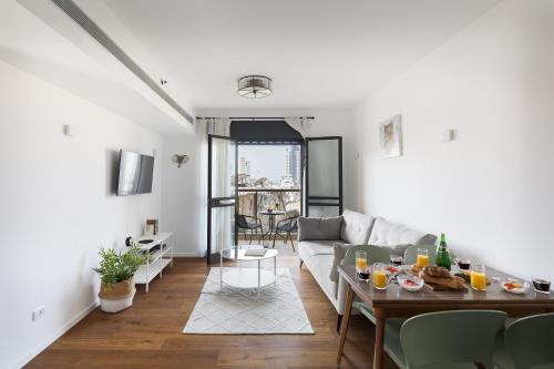 uma sala de estar com um sofá e uma mesa em Elegant Apartment w Balcony & Mamad in Heart of Tel Aviv by Sea N' Rent em Tel Aviv