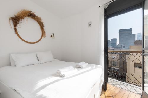 una camera con un letto bianco e una grande finestra di Elegant Apartment w Balcony & Mamad in Heart of Tel Aviv by Sea N' Rent a Tel Aviv