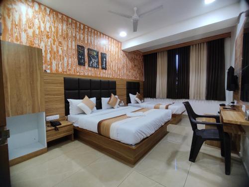 a hotel room with two beds and a desk and a desk at Hotel Newyork Inn in Anand