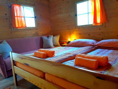 1 dormitorio con 1 cama con almohadas de color naranja en SočaLand Glamping, en Bovec