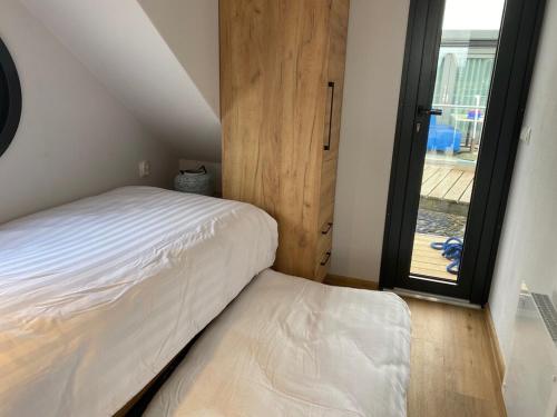 a bedroom with a white bed and a window at Modern houseboat with roof terrace, on Uitgeestermeer in Uitgeest