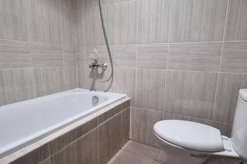 a bathroom with a toilet and a bath tub at Apt Vasanta Inopark 1 BR Lnd4 dgn Infinity Pool, Onsen dan Netflix in Jarakasta