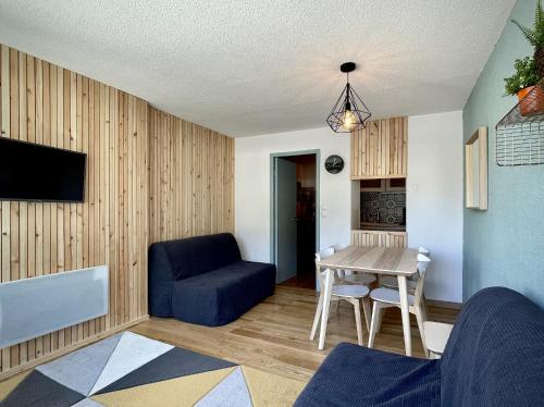 uma sala de estar com uma mesa e uma cadeira azul em Plein centre station vue imprenable em La Mongie