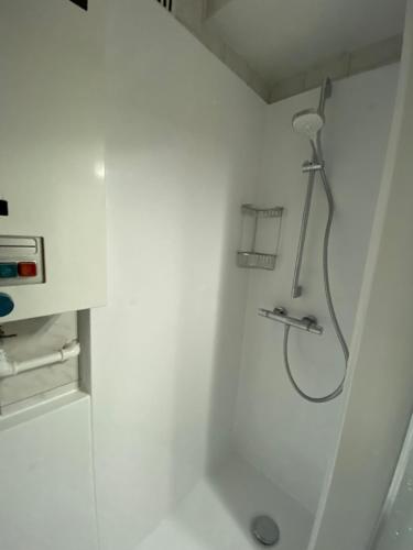 La salle de bains est pourvue d'une douche dans un mur blanc. dans l'établissement Appartement lumineux, idealement situe - Enfants bienvenus ACTIVITES COMMERCIALES OU REMUNEREES INTERDITES, à Namur