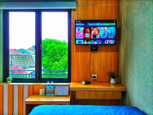 a bedroom with a tv and a bed and two windows at Cozy Residence Tomang in Jakarta