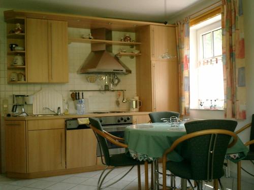kuchnia ze stołem z zielonymi krzesłami i kuchenką w obiekcie Ferienwohnung Nordsee w mieście Cuxhaven