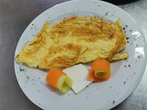 a white plate with an omelet and carrots on it at Hotel Dunav Požarevac in Požarevac