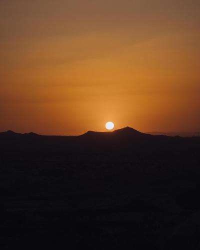 an orange sunset over a hill with the sun setting at Cappadocia Naif Hotel - Adults Only in Goreme
