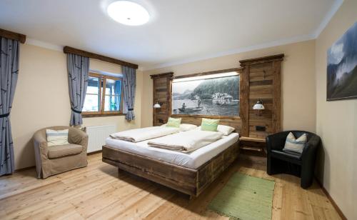 ein Schlafzimmer mit einem Bett, einem Stuhl und einem Fenster in der Unterkunft Landgasthof & Restaurant Batzenhäusl in Sankt Gilgen