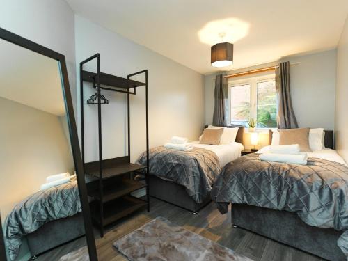 a bedroom with two beds and a mirror at Rothwell Close Serviced Two Bed Apartment in Telford