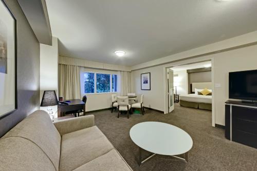 a living room with a couch and a table and a bed at Coast Kamloops Hotel & Conference Centre in Kamloops