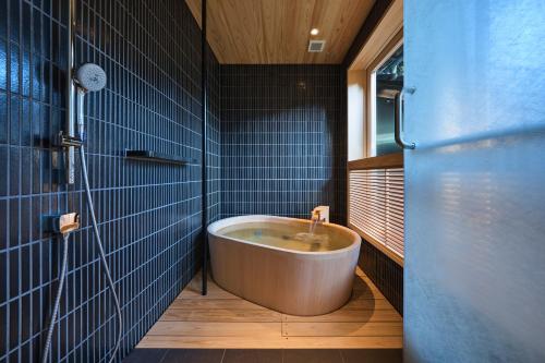 y baño con bañera y azulejos azules. en Nishimuraya Honkan, en Toyooka