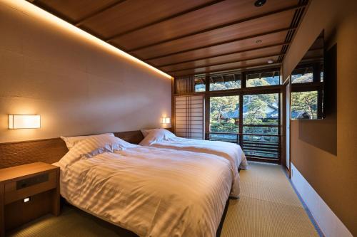 Un dormitorio con una cama grande y una ventana en Nishimuraya Honkan, en Toyooka