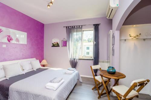 a bedroom with purple walls and a bed and a table at Apartment Tenega in Dubrovnik