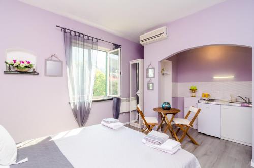 a room with two beds and a kitchen with purple walls at Apartment Tenega in Dubrovnik